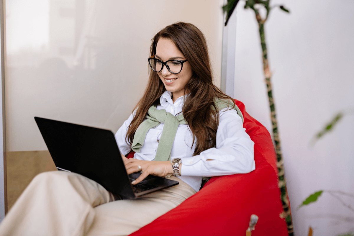 glimlachende vrouw achter laptop op rode stoel