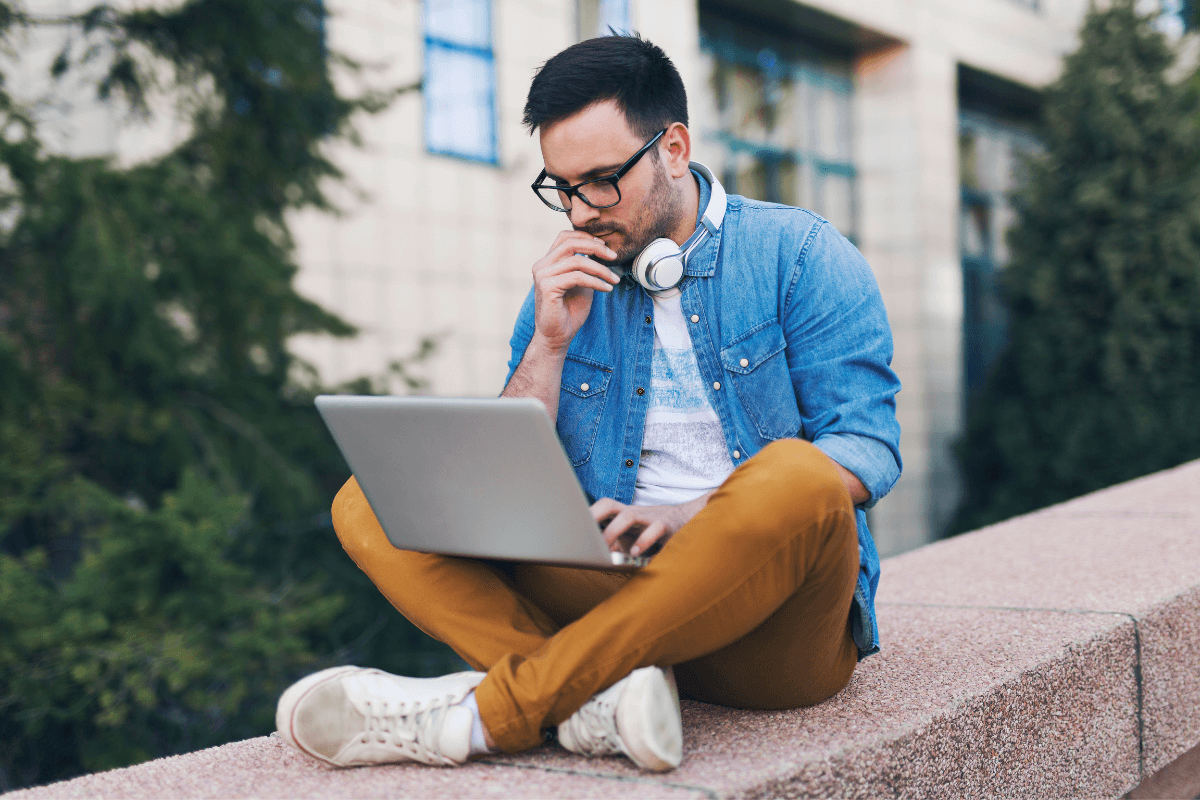 man met laptop op muurtje