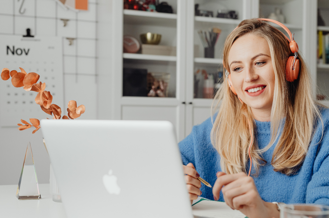 vrouw met koptelefoon achter laptop