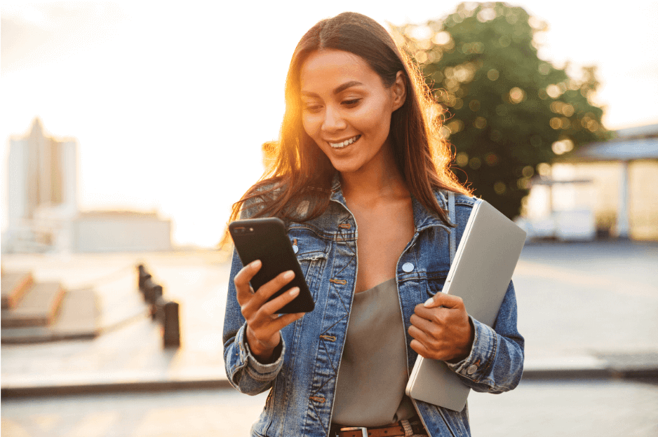 vrouw met telefoon in hand en laptop onder arm