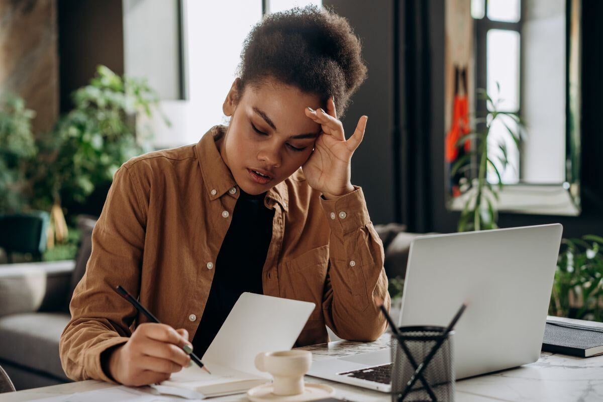 Vrouw met laptop die zorgelijk naar papieren kijkt