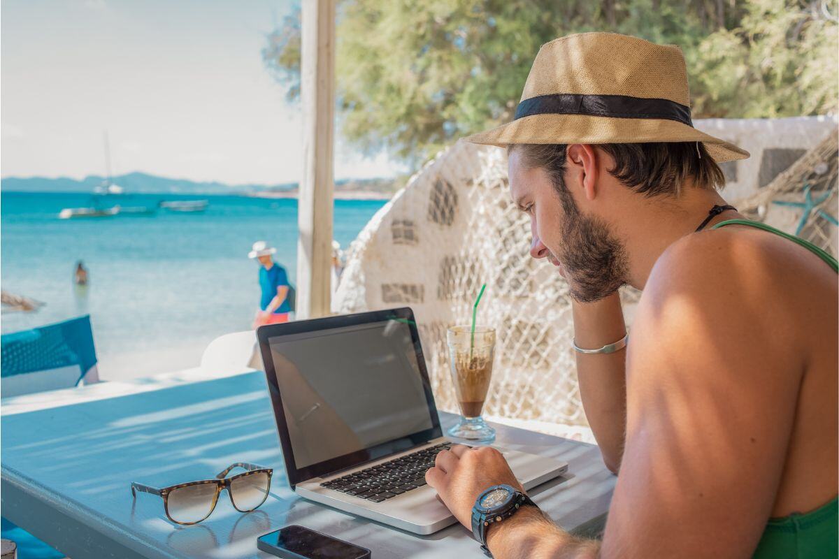 Man die werkt achter laptop met uitzicht op zee