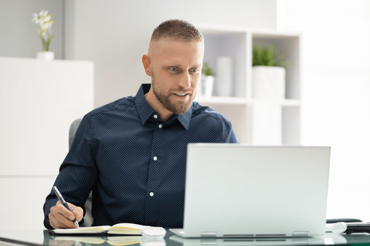 man achter laptop met notitieblok